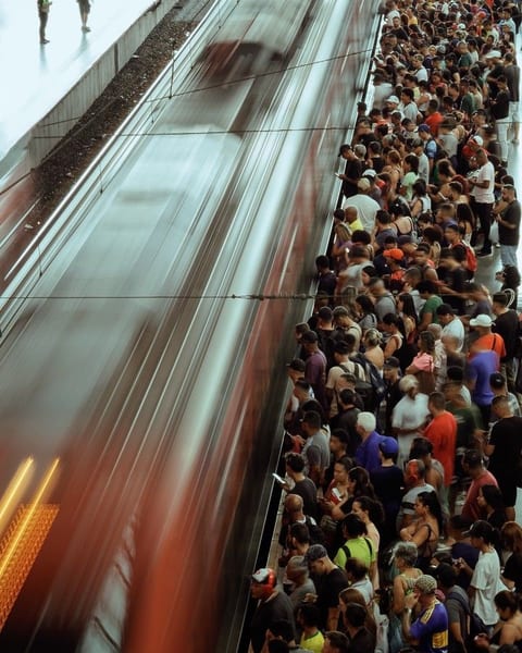 A crowded station platform beside a train blurred by its speed